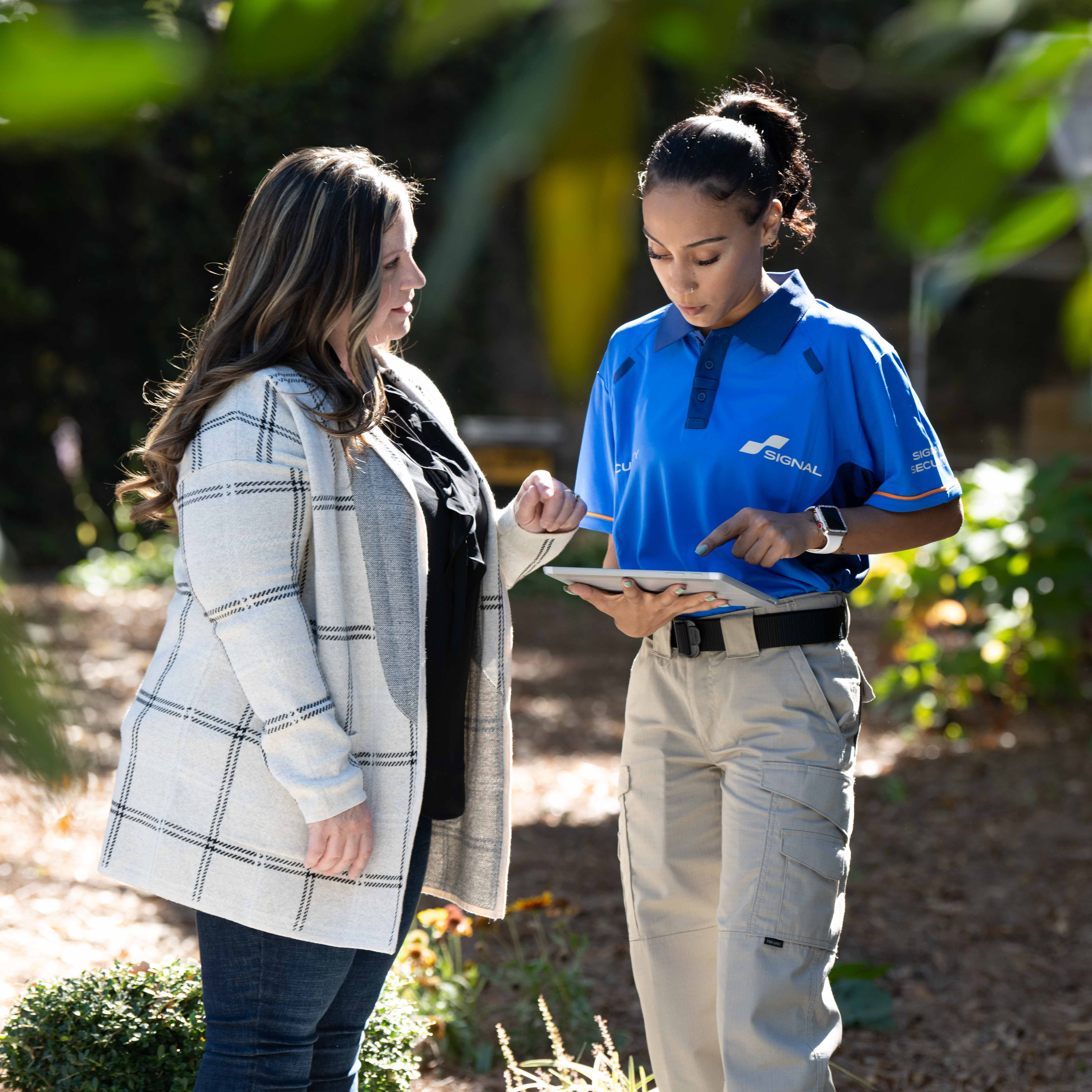 Team signal representative talking with a woman outdoors about security guard services. 